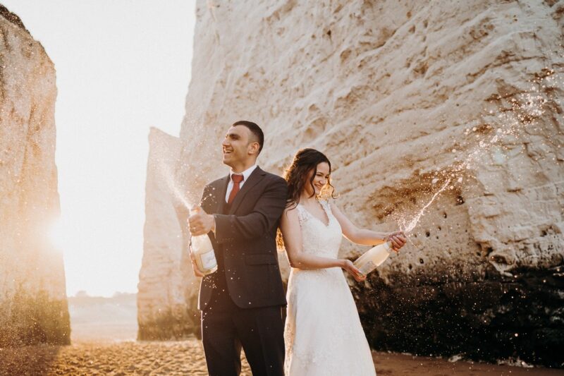 Bride and groom spraying Champagne on beach - Picture by Voyteck Photography