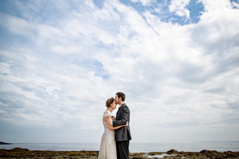 Groom kissing bride's head in front of beautiful cloudy blue sky - Picture by Brian Robinson Photography