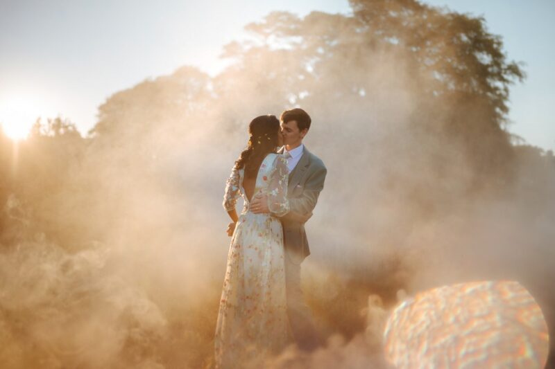 Bride and groom kissing in hazy sunshine surrounded by smoke - Picture by Joab Smith