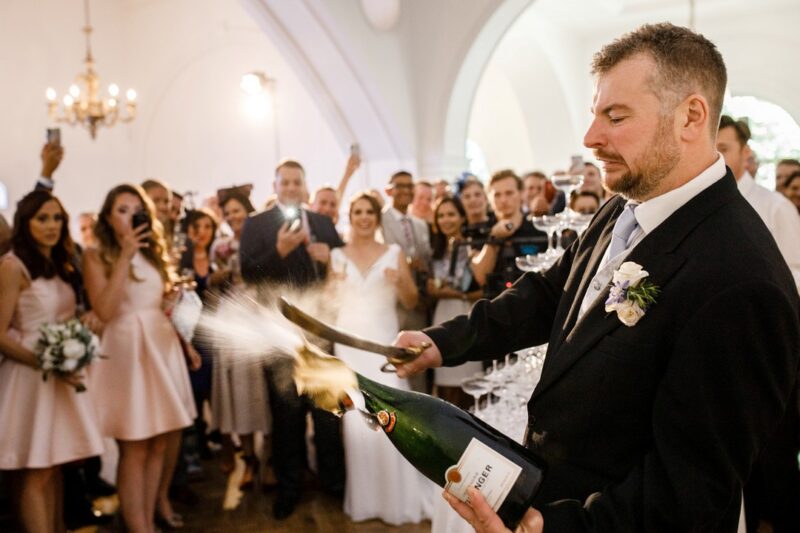 Man at wedding opening champagne bottle with sword - Picture by Damion Mower Photography