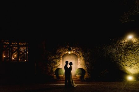 Bride and groom lit up as they stand in doorway of wedding venue at night - Picture by Murray Clarke