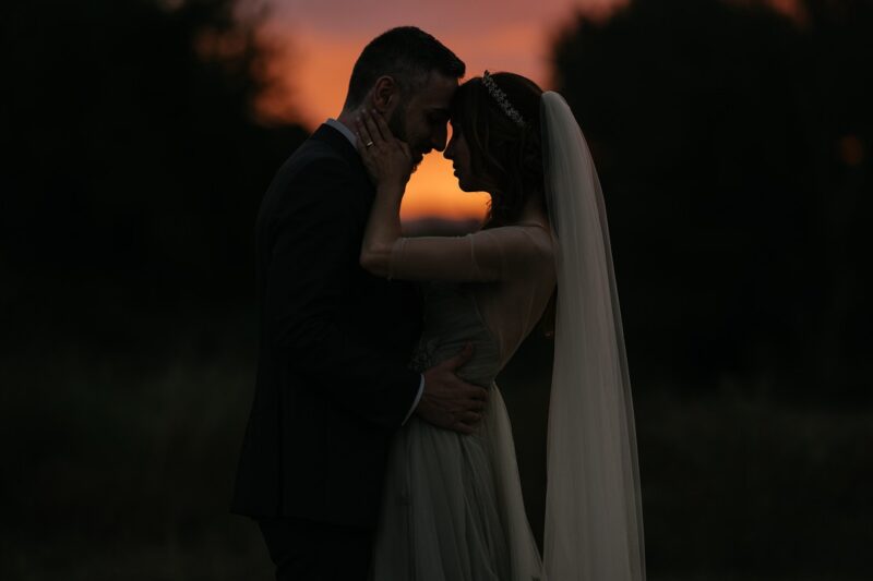 Bride and groom touching heads in dusk light - Picture by IstantiSenzaTempo