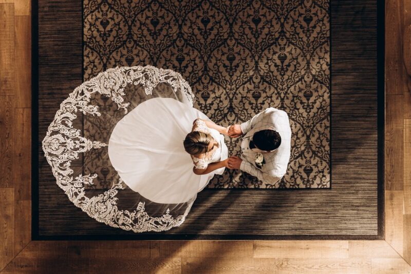 Aerial shot of bride facing groom with her elaborate dress train behind her - Picture by Angela Waites Photography
