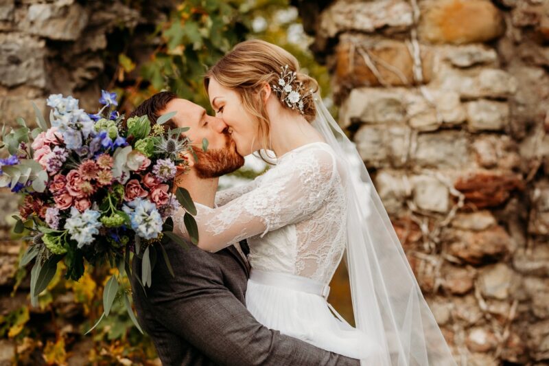 Bride holding bouquet kissing groom - Picture by When Charlie Met Hannah