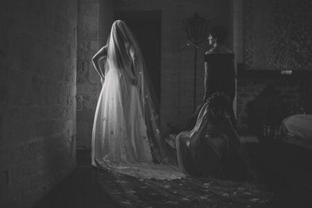 Bride standing in dark room lit by light through window - Picture by Rik Pennington Photography
