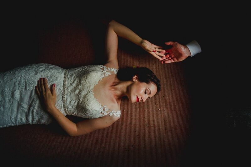 Bride laying on the floor touching groom's hand - Picture by Pollok Pictures