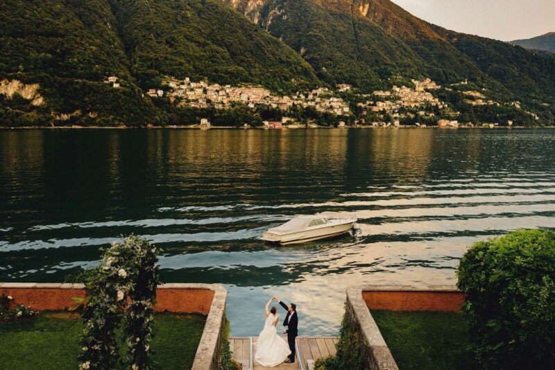 Groom twirling bride by water in Italy - Picture by MIKI Studios