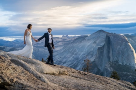 Groom leading bride by the hand at top of mountain - Picture by Bergreen Photography